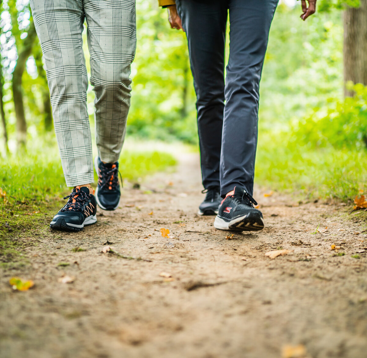 Twee personen wandelen met wandelschoenen aan door de natuur.