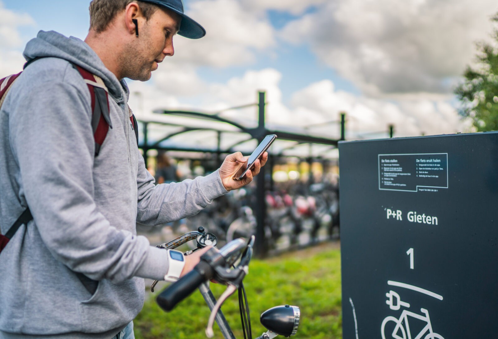 Een man gebruikt op zijn mobiel de app 'Fietskluizen' om een fietskluis te openen op een hub.